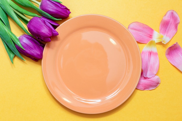 Tulips around orange dish with copy space on a yellow spring .