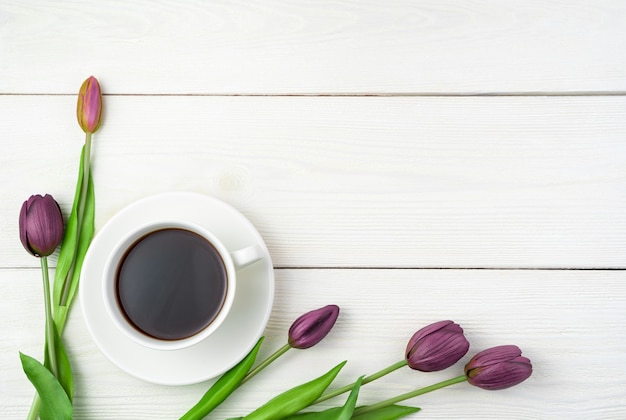 Tulips and a cup of coffee on a light background. Top view with space to copy.