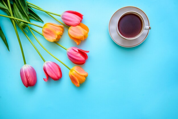 Tulips and a cup of tea or coffee on a blue background