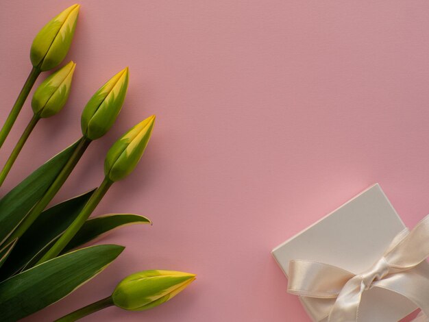 チューリップの花の白いギフト ボックス、弓と紙の背景にコピー スペース