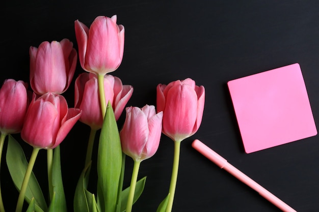 Tulips and notebook for writing on black