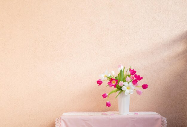 背景の壁のテーブル上の花瓶の中のチューリップ