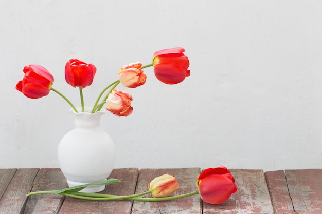 Tulips in vase on white old background