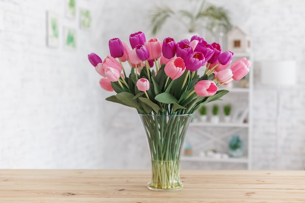 Tulipani in un vaso su un tavolo di legno. interni scandinavi.