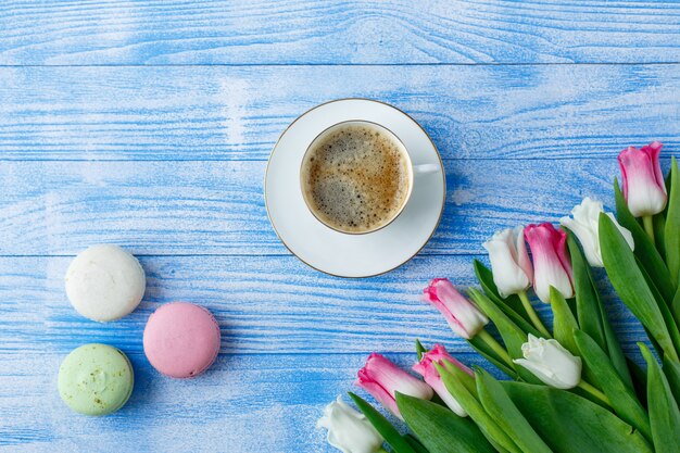 Tulips with macaroons on blue wooden surface