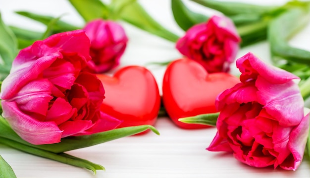 Фото Тюльпаны с двумя красными сердцами на белом деревянном фоне