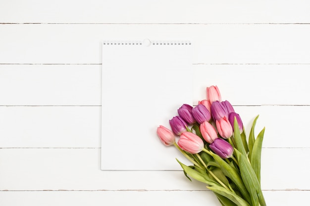 Tulips with white paper on wooden texture. Valentine's Day template with copy space