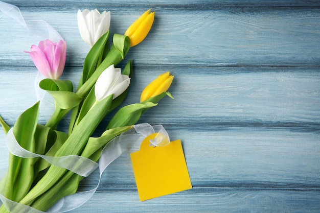 Tulpen en lege kaart op houten achtergrond bovenaanzicht