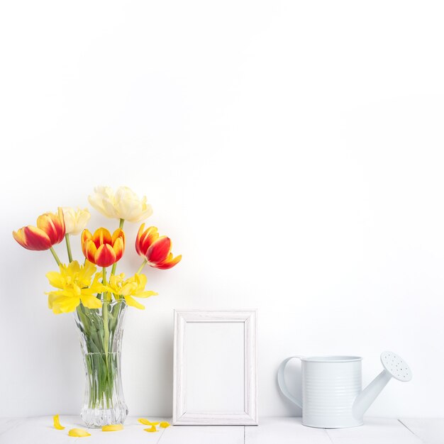 Tulpenbloem in glasvaas met fotolijstplaats op witte houten tafel achtergrond tegen schone muur thuis, close-up, Moederdag decor concept.