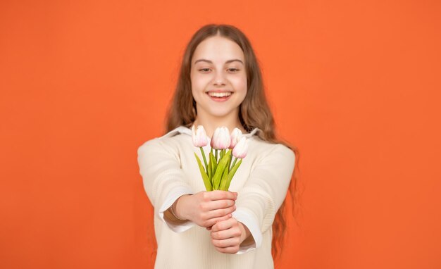 Tulpenbloemen in handen van gelukkig kind op oranje achtergrond, selectieve aandacht, moederdag