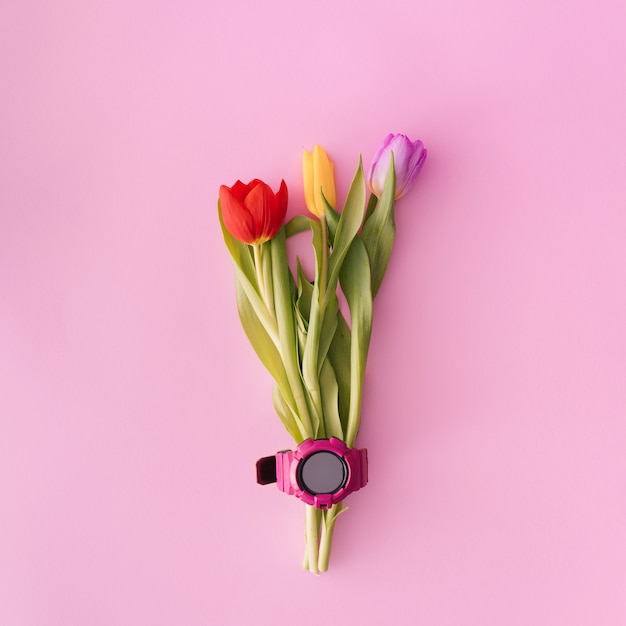 Tulpenboeket met een roze horloge op pastelkleurige achtergrond. creatieve plat lag kopieerruimte.