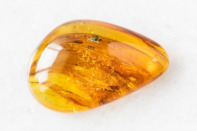 Tumbled Amber gem stone on white marble