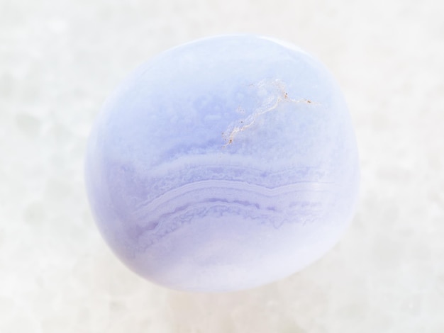 Photo tumbled blue chalcedony gemstone on white marble