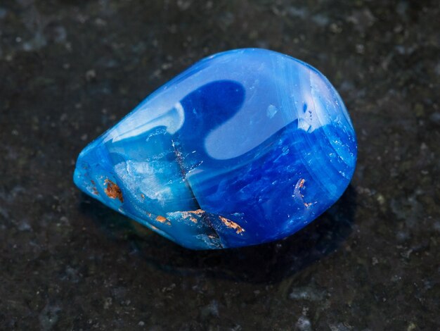 Photo tumbled blue toned agate gemstone on dark