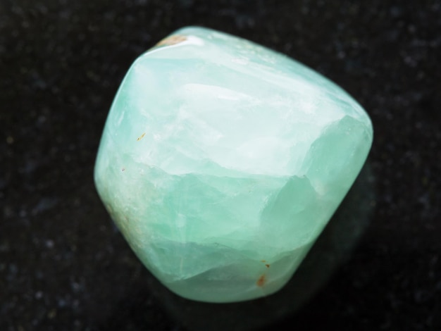 Tumbled Prehnite gemstone on dark background