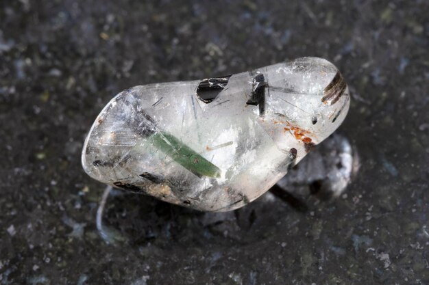 Tumbled quartz gemstone with Tourmaline on dark