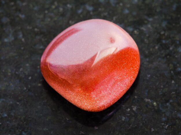 Tumbled red goldstone gemstone on dark