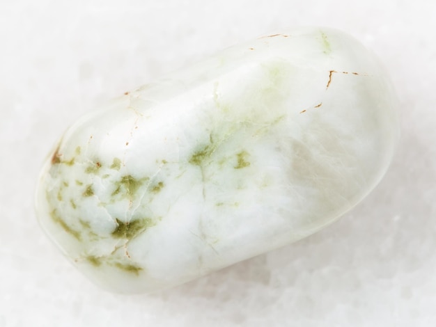 Tumbled vesuvianite gemstone on white marble