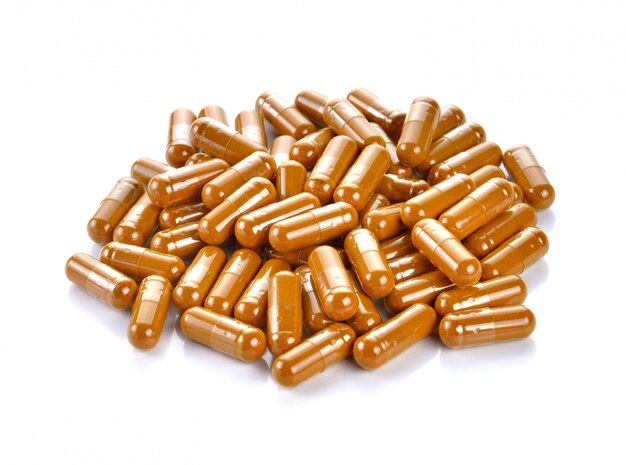 Tumeric powder capsules on white background