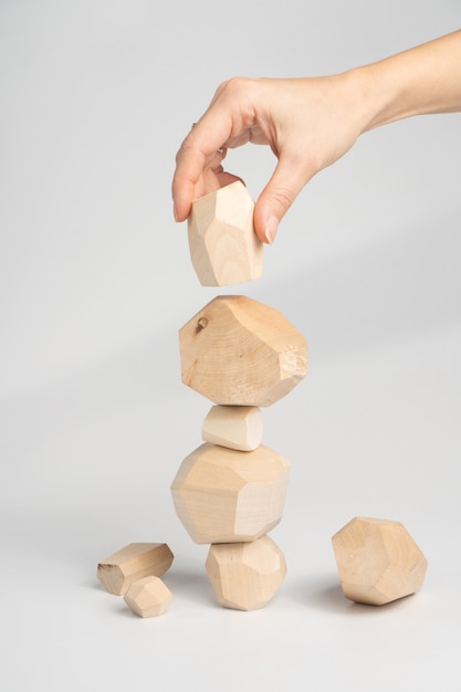 ツミイシパズルゲーム。女性または少女は、不安定な塔の上にある別の木のブロックに手を置きます。