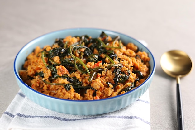 Tumis kangkung oncom or vegetable stir fried water spinach on a blue plate