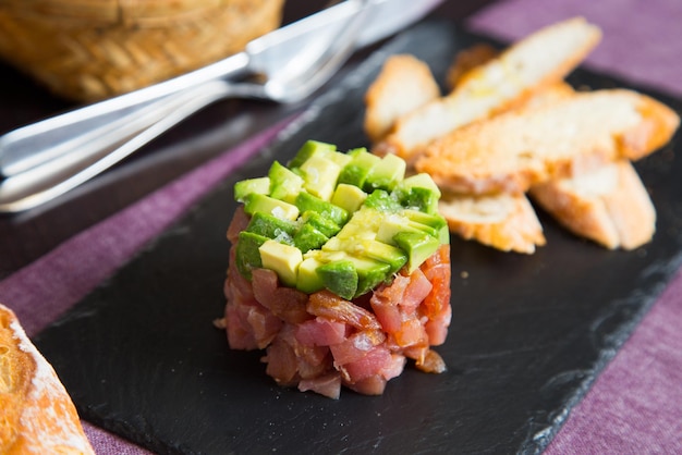 Foto tartare di tonno e avocado. la tartare di tonno è un piatto semplice composto da tonno crudo tagliato a cubetti