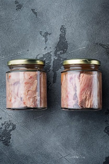 Tuna fillet meat in glass jar on gray background flat lay