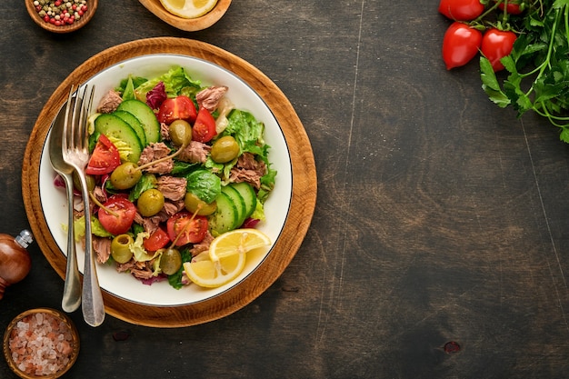 tuna salad with fresh vegetables, olives, capers and lemon served in bowl