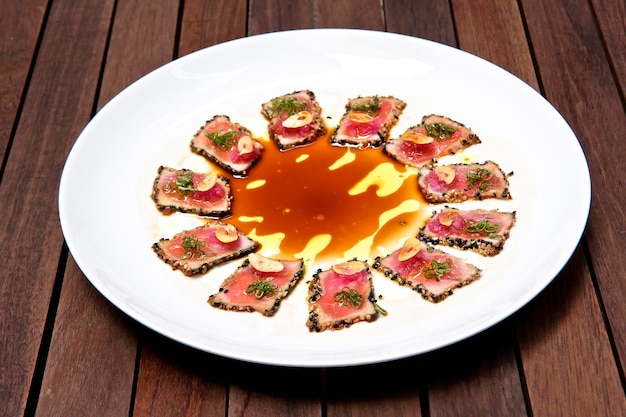 Tuna sashimi fried tuna fillet with black sesame olive oil and teriyaki sauce white plate food
