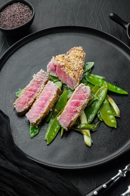 Tuna steak grilled with spring onions and sugar snap peas set, on plate, on black stone