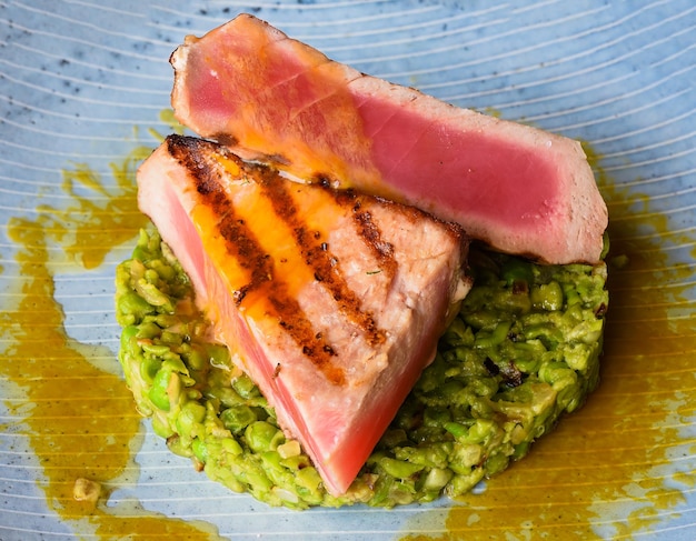 Tuna steak medium rare served with peas isolated on black background top view