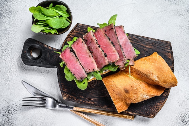 Tuna steak sandwich in a baguette with arugula.