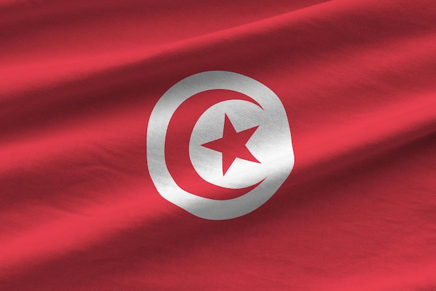 Tunisia flag with big folds waving close up under the studio light indoors the official symbols and