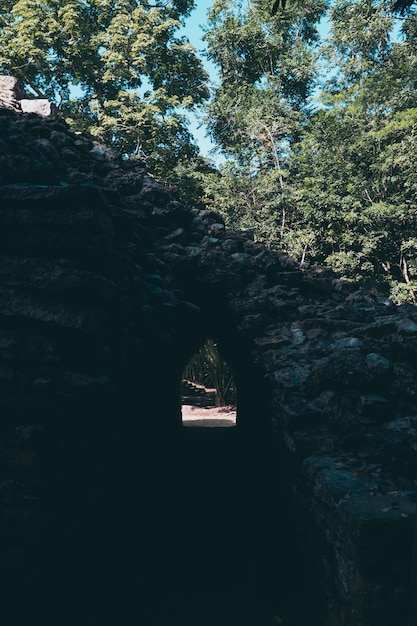 Un tunnel tra le rovine maya con alberi dietro in coba