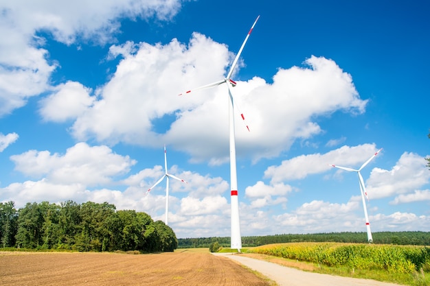 Turbines on field on cloudy blue sky. Wind farm in Lower Saxony, Germany. Global warming, climate change. Alternative energy source. Eco power, green technology concept.