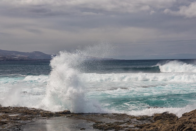 Turbulent ocean waves with white foam beat coastal stones