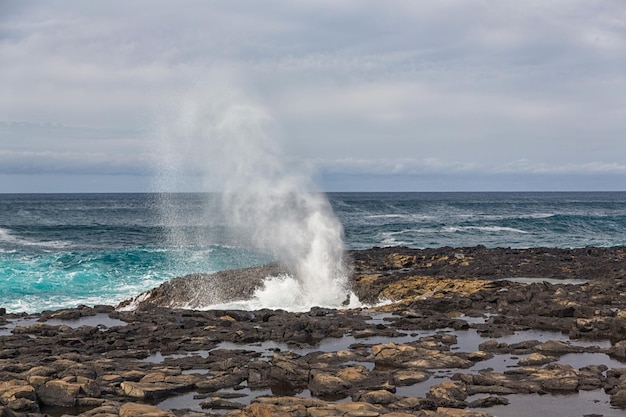 Turbulent ocean waves with white foam beat coastal stones