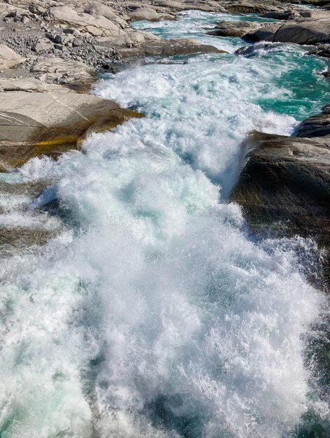 Турбулентная вода горного ручья разбивается о скалы великой силой природы
