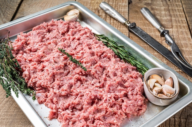 Turkey or chicken mince raw meat in a kitchen tray. Wooden background. Top View.