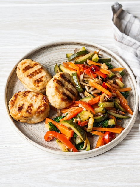 Turkey cutlets grill, vegetables steer fry on a plate on wood board table.