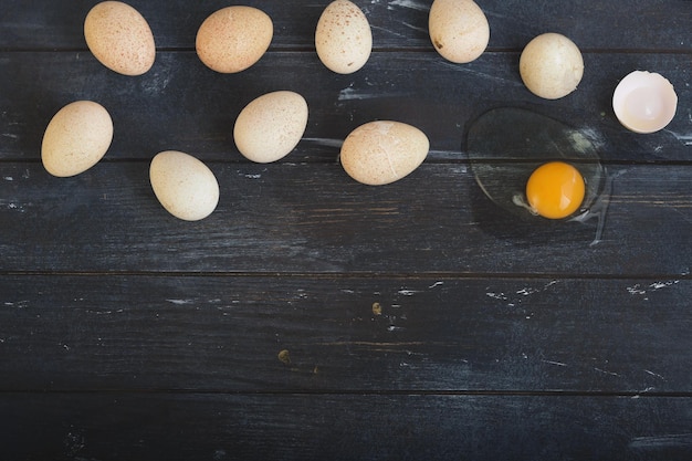 Turkey eggs and one broken egg on rough dyed wooden surface