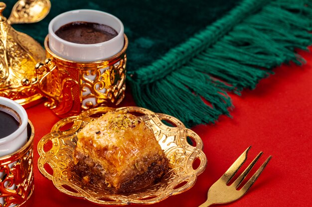 Turkish baklava and coffee in oriental dishware on red background