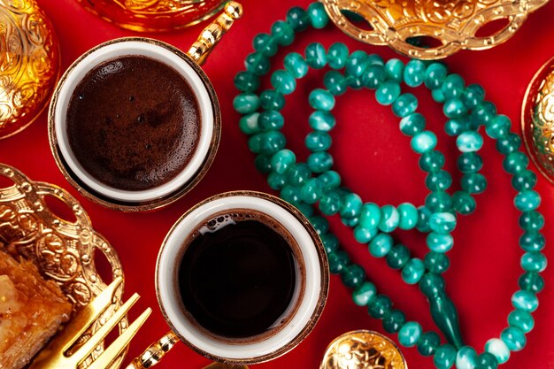 Turkish baklava and coffee in oriental dishware on red, top view