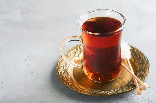 Turkish black tea Glass cup of turkish black tea and crispy Turkish traditional bagel on gray concrete table background Breakfast pastry concept Traditional turkish brewed hot drink