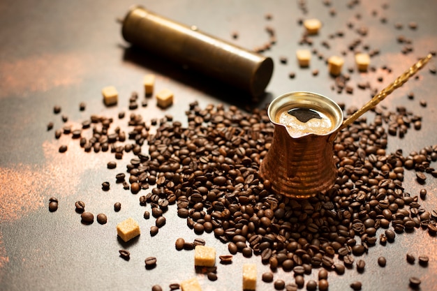 Turkish coffee concept. Copper coffee pot (Cezve), vintage coffee grinder, coffee beans and sugar on a dark vintage background. Close-up