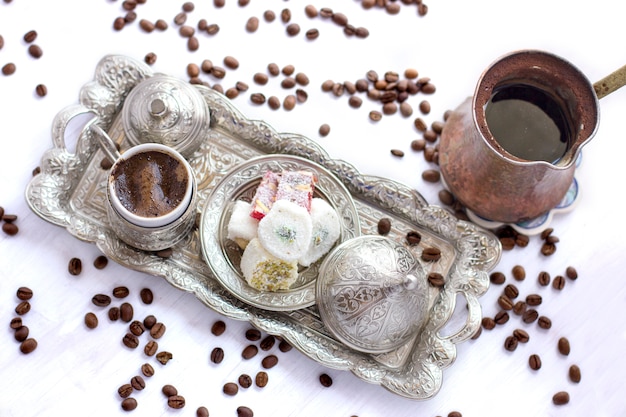 Turkish coffee with traditional turkish sweets in silver mug and jezve