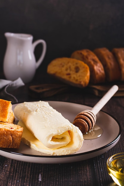 Турецкий сливочный молочный каймак, мед и хлеб на завтрачной тарелке вертикальный вид