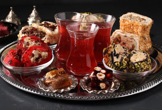 Turkish delight and pomegranate tea on metal tray on dark surface, Closeup, Horizontal format