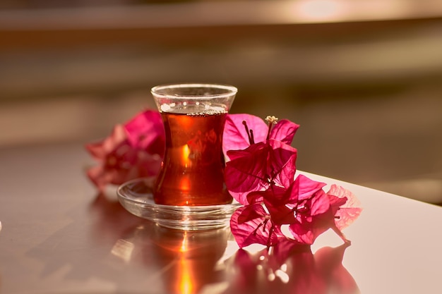 Turkish delight and traditional glass of turkish tea with bougainvillea flowers Romantic dinner concept Relaxing calming drink Travel Turkey concept Bright relaxing drink High quality photo