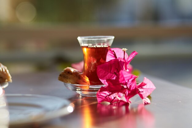 Turkish delight and traditional glass of turkish tea with bougainvillea flowers Romantic dinner concept Relaxing calming drink Travel Turkey concept Bright relaxing drink High quality photo